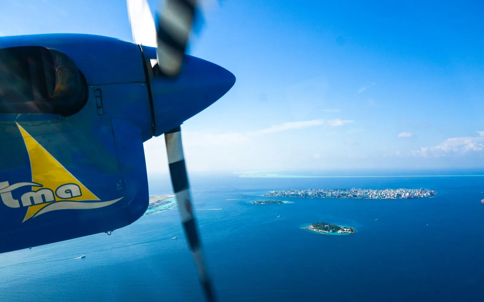 Seaplane flying over clear Maldives lagoons