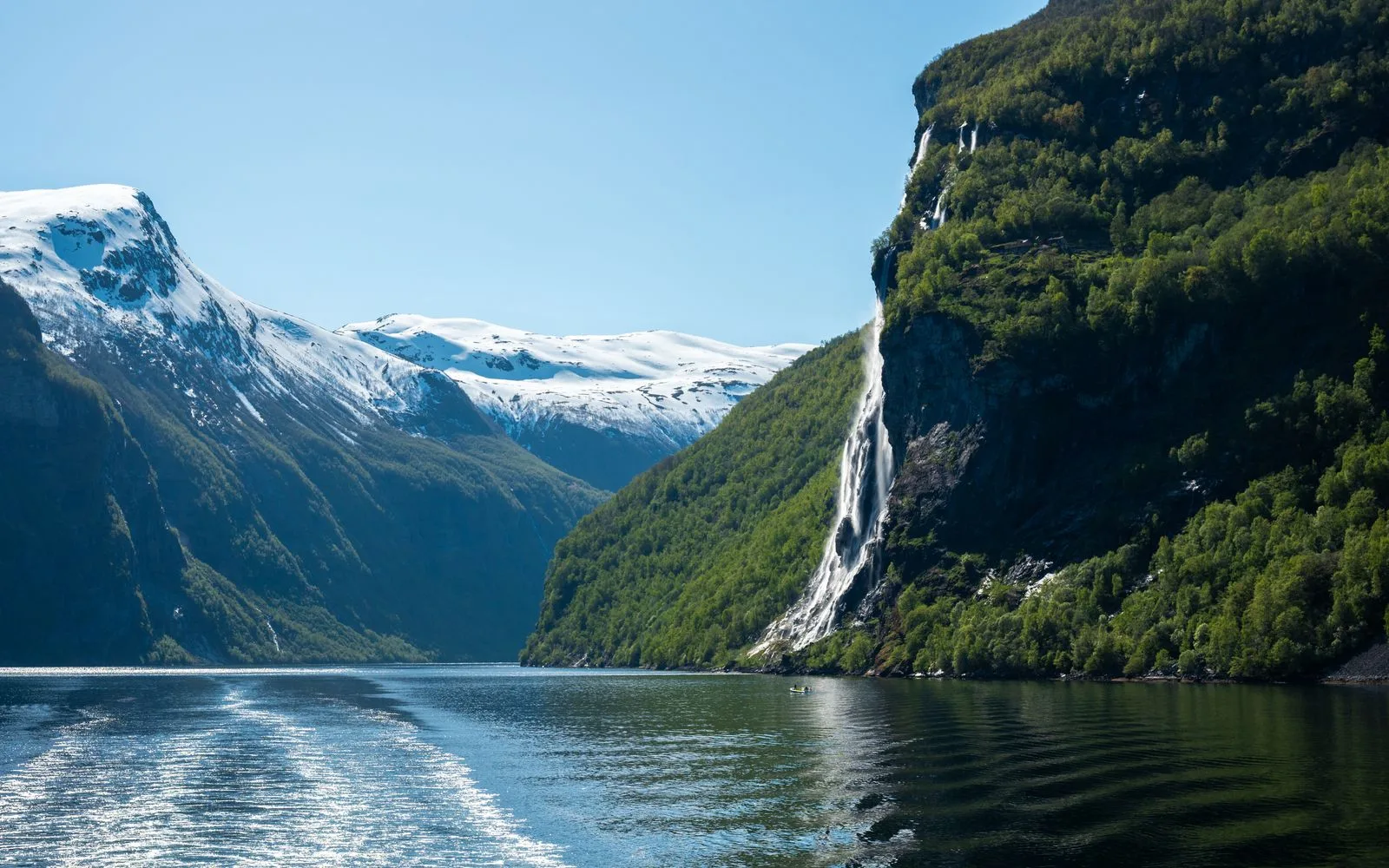 Waterfall and snow-capped mountains above Geirangerfjord, Norway